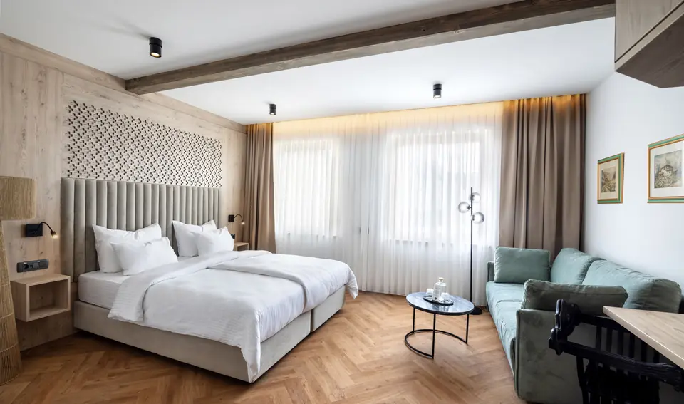 Double room with forest-green sofa at Hotel Julian Alps near Bled